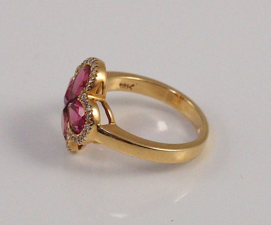A modern 18k gold four stone pear shaped pink tourmaline set dress ring with diamond chip set border